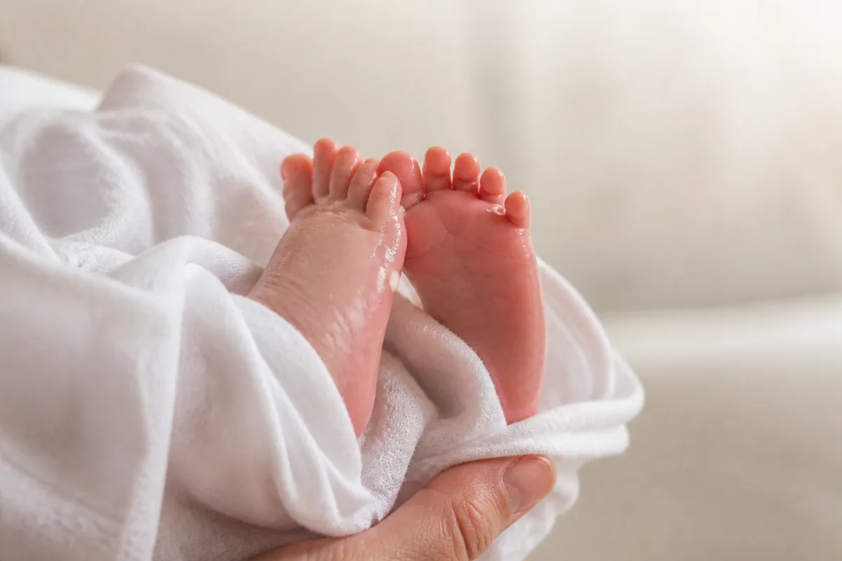 Pieds de nouveau-né enveloppés dans un lange de coton clair après le bain
