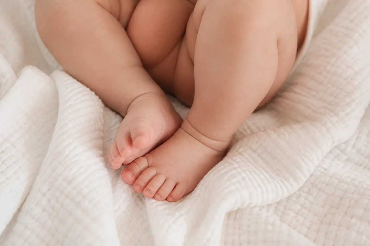 Gros plan sur des pieds de bébé nus posés sur une couverture en coton gaufré